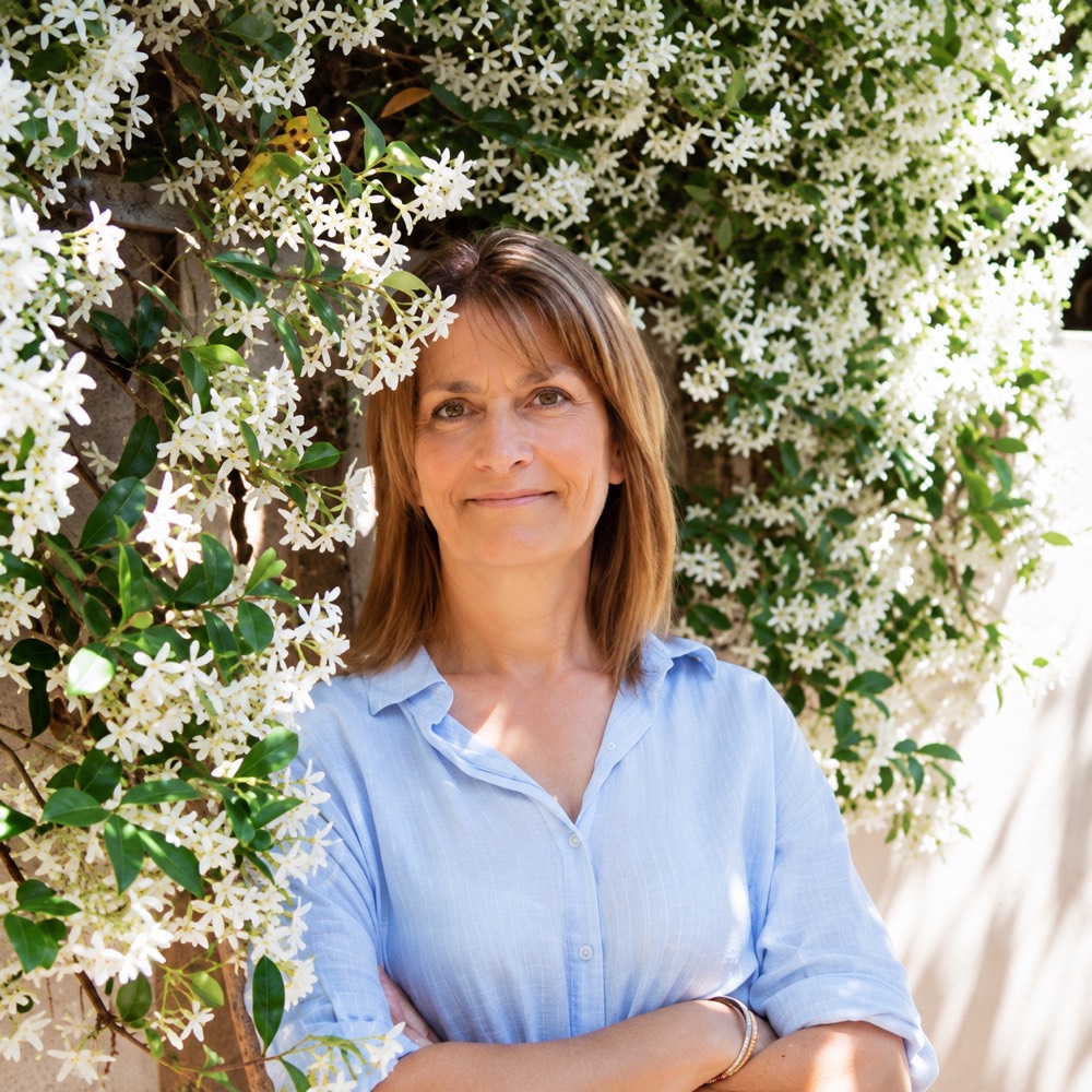 Virginie Chaumet, praticienne en hypnose régressive quantique au Plan-de-la-Tour, souriante devant un jasmin en fleurs